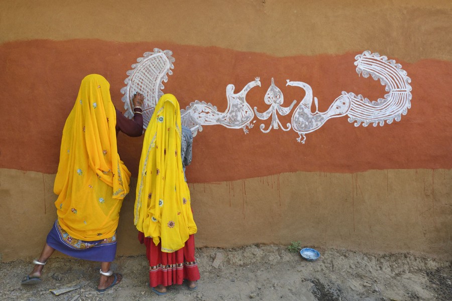 India, Rajasthan, Tonk region, Women painting clay walls prior to Diwali festival.